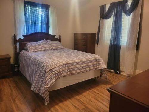 a bedroom with a bed and a dresser and windows at Central located large home on quiet wooded street in Lumberton