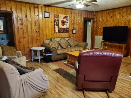 a living room with leather furniture and a flat screen tv at Central located large home on quiet wooded street in Lumberton