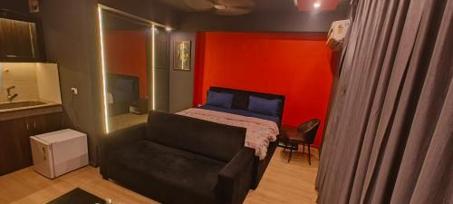 ラクナウにあるDLF Stay innのベッドとソファがあり、赤い壁がある寝室
