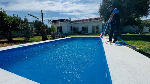 a man with a mop in front of a swimming pool at Luxury Villa with Pool & Garden5km from Cabo in Tetouan