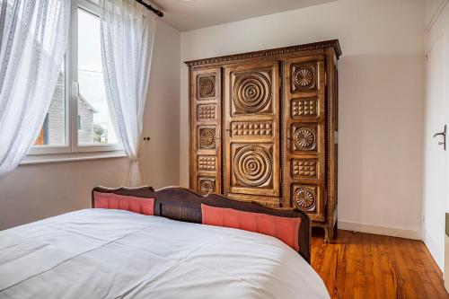 a bedroom with a large wooden headboard and a bed at Authentic Ty Parc Hamon in Ploujean