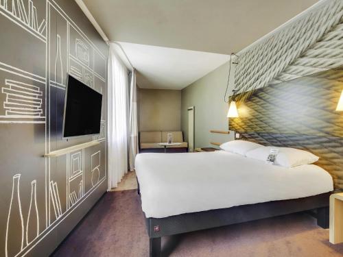 a hotel room with a large bed and a flat screen tv at ibis Saint Germain en Laye Centre in Saint-Germain-en-Laye