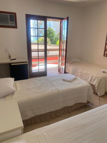 a room with two beds and a door to a balcony at Pousada Ana Julia in Florianópolis