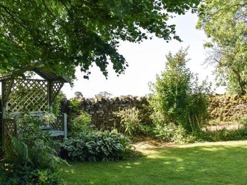 a garden with a stone wall and a fence at The Barracks in Little Strickland