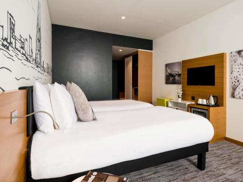 a hotel room with a large bed and a tv at ibis Styles Manama Diplomatic Area in Manama
