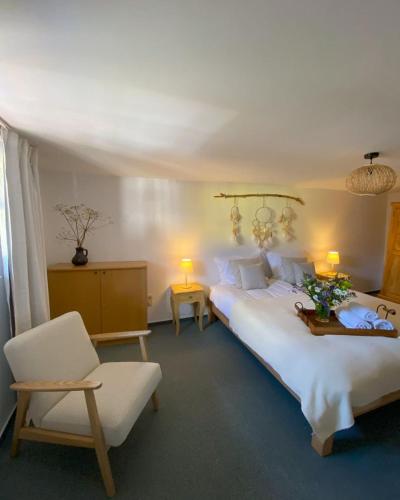 a bedroom with a large white bed and a chair at Auszeit Ferienhaus Nr 2 in Sierscheid