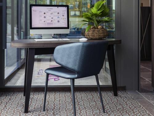 a desk with a computer monitor and a chair at Mercure Blankenberge in Blankenberge