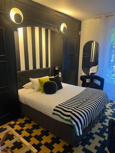 a bedroom with a large bed with a black and white blanket at Hotel Du Croisé in Marcq-en-Baroeul