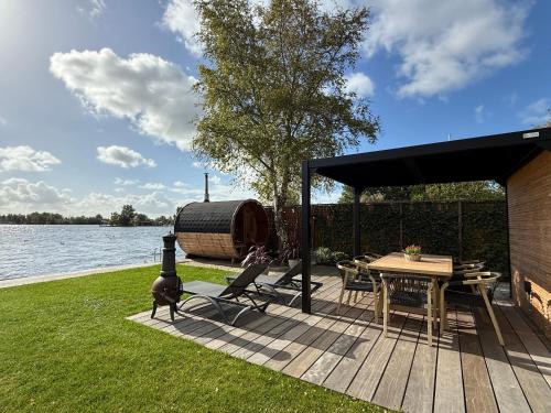 a wooden deck with a table and a boat at Villa Perla Mare - Sauna Experience - On a lake near Amsterdam in Vinkeveen
