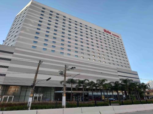 a large hotel building with palm trees in front of it at ibis Sao Paulo Ibirapuera in Sao Paulo