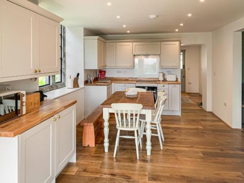a kitchen with white cabinets and a wooden table and chairs at The Old School in Kettlewell