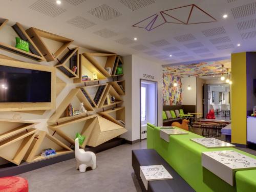 a living room with a green couch and a wall of shelves at ibis Styles Nantes Centre Gare in Nantes
