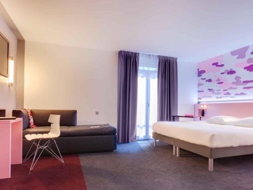 a hotel room with a bed and a couch at ibis Styles Nantes Centre Gare in Nantes