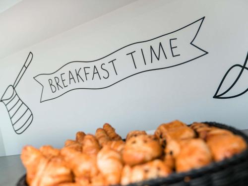 a sign that reads breakfast time with a basket of pastries at ibis Styles Nantes Centre Gare in Nantes