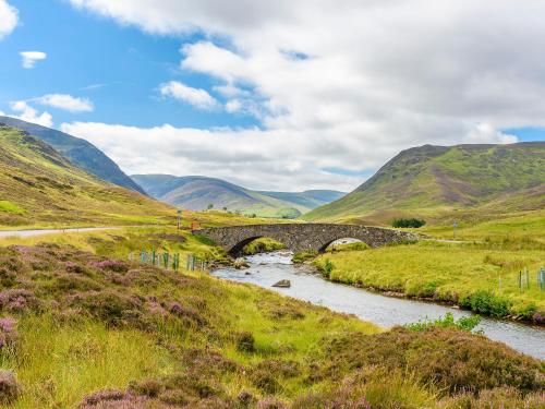 a stone bridge over a river in the hills at Ardle Lodge in Enochdhu