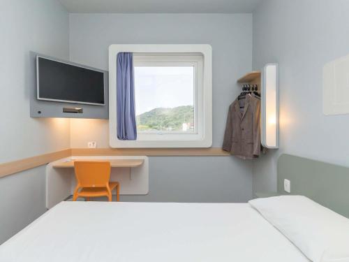 a room with a bed and a desk and a window at ibis budget Blumenau in Blumenau