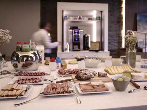 a table with meats and cheeses and other food items at Novotel Saint Brieuc Centre Gare in Saint-Brieuc