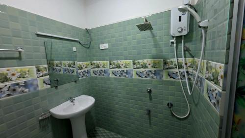 a green tiled bathroom with a sink and a shower at Meegahapokuna Resort in Anuradhapura
