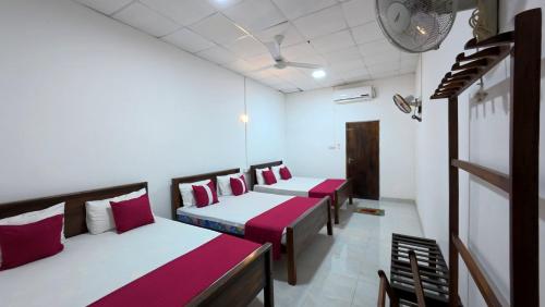 a room with four beds with red and white sheets at Meegahapokuna Resort in Anuradhapura