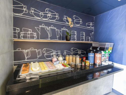 a buffet line with food on a blue wall at ibis budget Blumenau in Blumenau