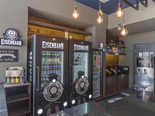 a bar with two refrigerators with drinks in them at ibis budget Blumenau in Blumenau