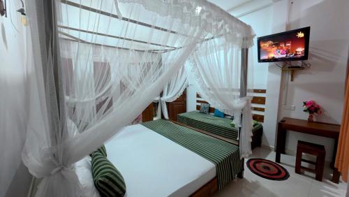 a bedroom with a bed with curtains and a television at Meegahapokuna Resort in Anuradhapura
