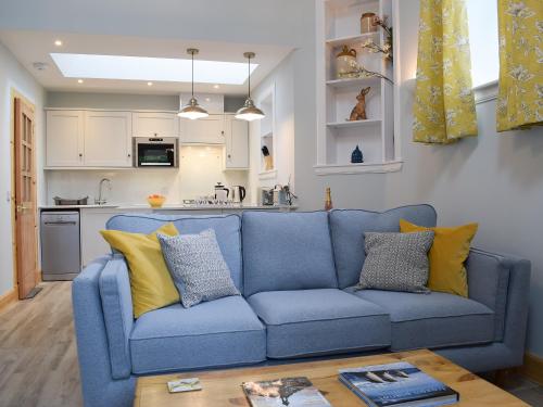 a blue couch in a living room with a kitchen at The Old Stables At Westerton in Crieff