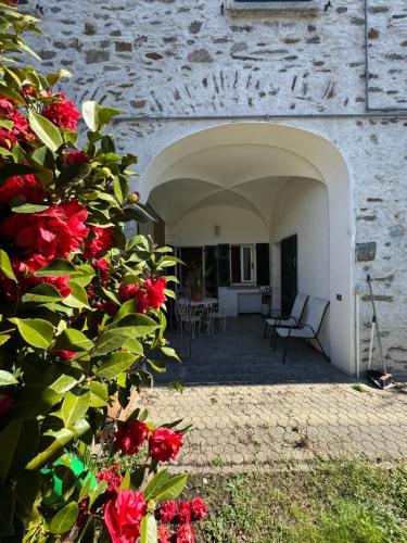 a courtyard with red flowers and a stone building at Cà du lac in Dervio