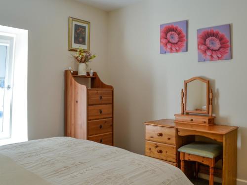 a bedroom with a bed and a dresser and a mirror at Holly - Apartment in Aberfoyle
