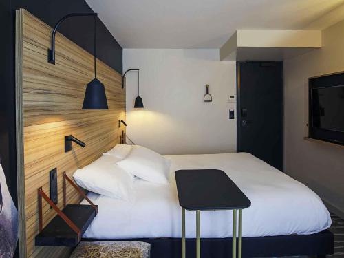 a bedroom with a white bed and a table at ibis Styles Laval Centre Gare in Laval
