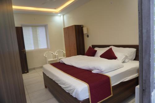 a bedroom with a bed with white sheets and red pillows at 7Sky Hotel and Restaurant in Bhojpur