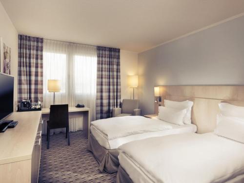 a hotel room with two beds and a desk at Mercure Hotel Mannheim am Friedensplatz in Mannheim