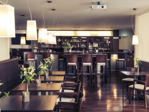 a restaurant with tables and chairs and a bar at Mercure Hotel Mannheim am Friedensplatz in Mannheim