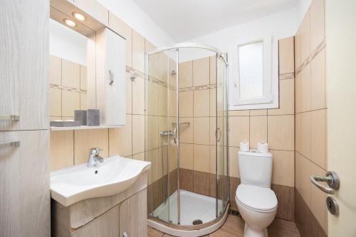 Un baño con inodoro, lavabo y ducha. en Villa Magda Dione, en (( Klonátika ))