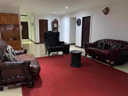 a living room with leather furniture and a red carpet at Homely Palace Guesthouse in Midrand