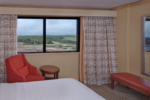 a room with a bed and a chair and a window at Sheraton Hartford Hotel at Bradley Airport in Windsor Locks