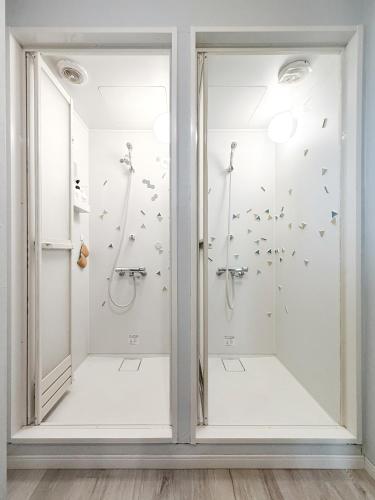 two shower stalls in a bathroom with birds on the wall at Gallery House in Tokyo