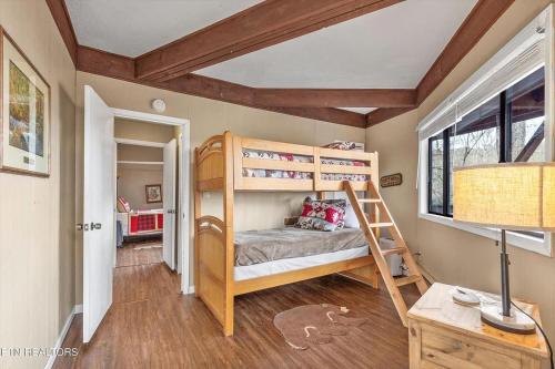 a bedroom with bunk beds and a desk with a lamp at Hideaway Chalet - Hot Tub in the Treetops, Arcade Games, + Close to Ober Mountain! in Chalet Village