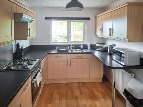 a kitchen with wooden cabinets and a sink and a microwave at Seacroft in Cromer