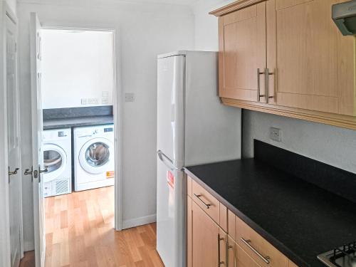 a kitchen with a refrigerator and a washer and dryer at Seacroft in Cromer