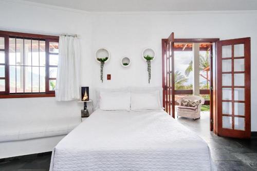 a bedroom with a large white bed and a window at Chalés Mirante da Lagoinha in Ubatuba