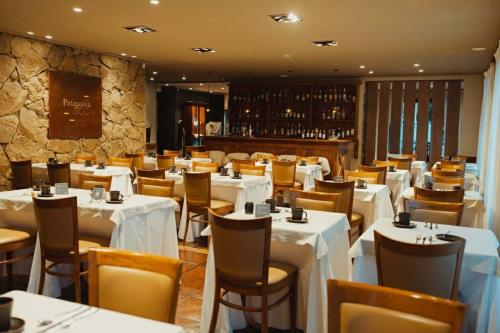 a dining room with white tables and chairs at Calafate Parque Hotel in El Calafate