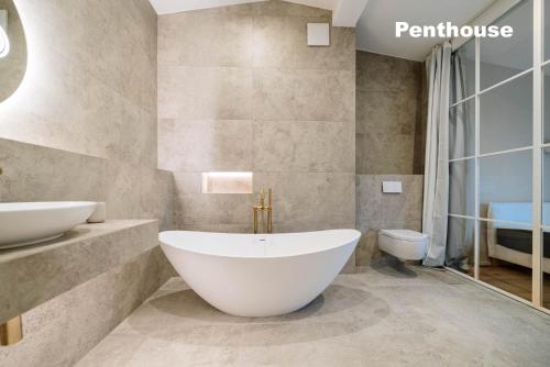 a bathroom with a large white tub and a toilet at Lindgold in Munich