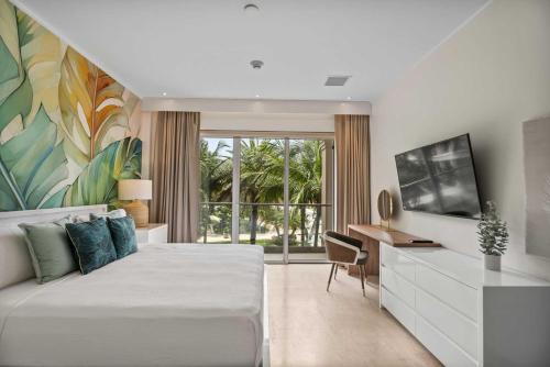 a bedroom with a bed and a desk and a tv at Eagle Beach - Palm by the Sea 2BR condo - LV207 in Palm-Eagle Beach