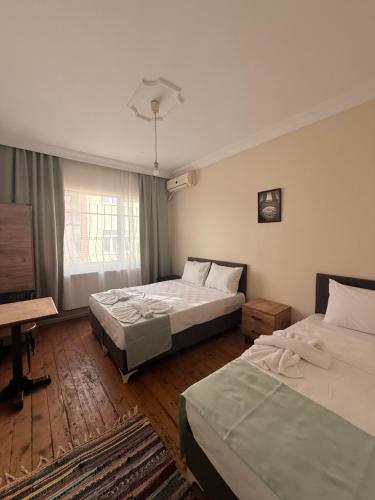 イスタンブールにあるwalkabout apartのベッド2台と机と窓のある寝室