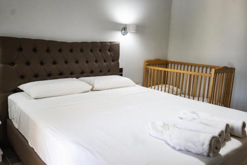 a bedroom with a large white bed with a crib at Hill Sun Luxury Suites in Nea Iraklia
