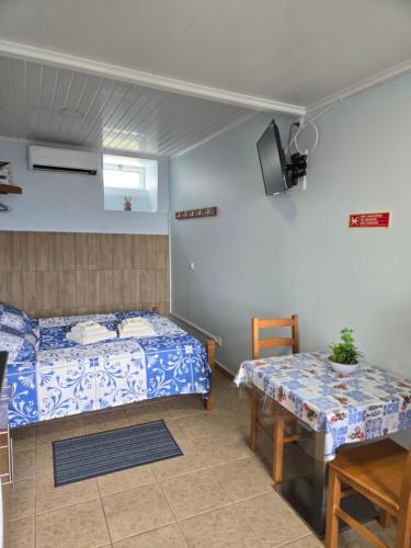 a bedroom with two beds and a table and a tv at Rainha do Mar AL 3436 in Fontinhas