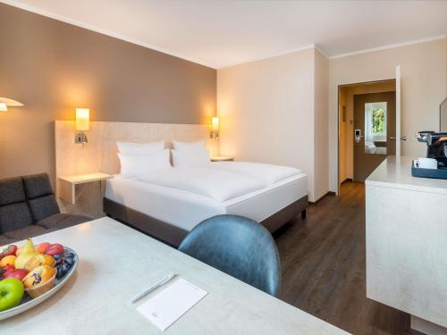 a hotel room with a bed and a bowl of fruit at Mercure Hotel Bielefeld Johannisberg in Bielefeld