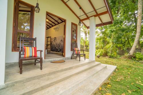 a porch of a house with two chairs on it at Bird Of Paradise - Ahangama Villa in Ahangama