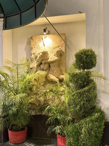 Una estatua de un hombre leyendo un libro en una pared con plantas. en Hotel Diplomat Residency, en Bareilly